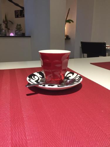 
a red coffee cup sitting on top of a red table at Platinum Suites Fremantle in Fremantle
