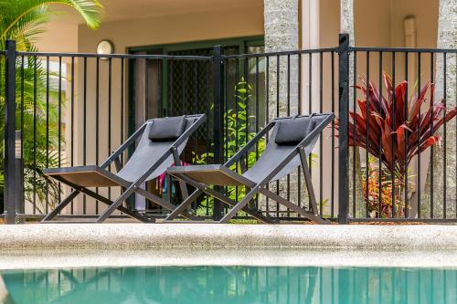 two chairs sitting next to a fence next to a pool at Beaches Apartments Byron Bay in Byron Bay