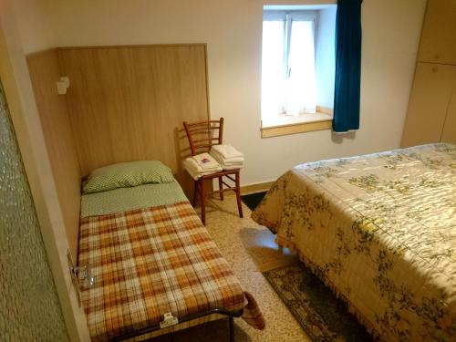 Un dormitorio con una cama, una silla y una ventana en Casa San Martino, en Teglio