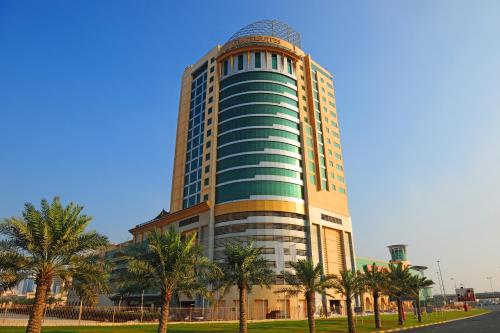 a tall building with palm trees in front of it at Fraser Suites Seef Bahrain in Manama