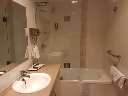 a bathroom with a tub, sink and mirror at Vine Inn Barossa in Nuriootpa