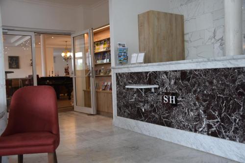 a lobby with a red chair and a counter at Seehotel Herlinde in Podersdorf am See