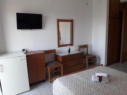 1 dormitorio con cama, tocador y espejo en Posidonia Pension, en Amarinto