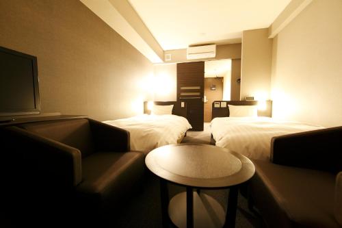 a hotel room with two beds and a couch at Dormy Inn Kagoshima in Kagoshima