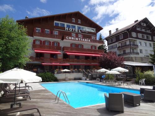 ein Hotel mit einem Pool vor einem Gebäude in der Unterkunft Hotel Christiania in Villard-de-Lans