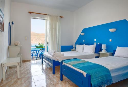 a blue and white bedroom with two beds and a window at Faros Rooms in Livadia