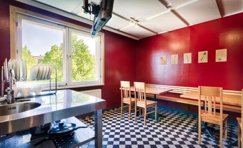 - une cuisine aux murs rouges avec une table et des chaises dans l'établissement Eurohostel, à Helsinki