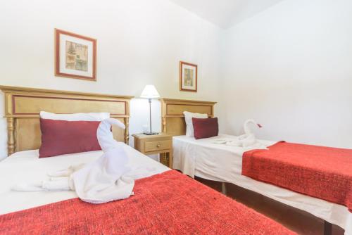 a bedroom with two beds with red and white sheets at Huerta la Pimentada in Palma del Río
