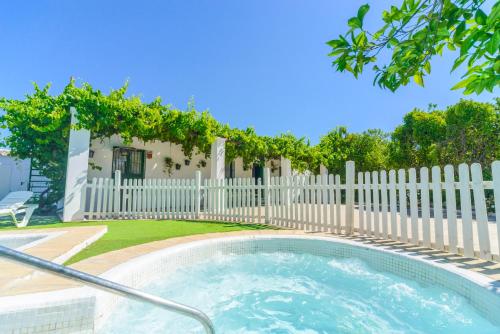 a hot tub in a backyard with a white fence at Huerta la Pimentada in Palma del Río