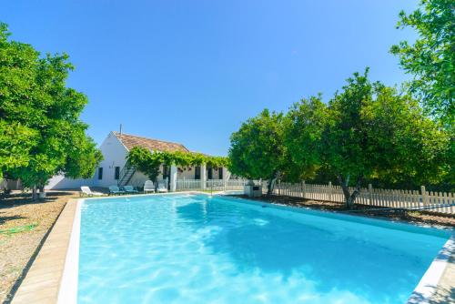 a swimming pool in a yard with trees and a fence at Huerta la Pimentada in Palma del Río