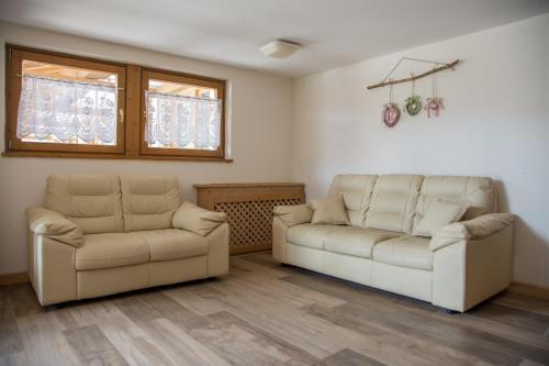 a living room with two white couches and two windows at Caminetto Mountain Resort in Lavarone