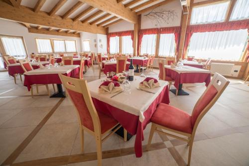 a restaurant with tables and chairs with red tablecloths at Caminetto Mountain Resort in Lavarone