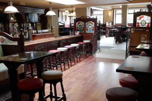 a bar with a row of stools in a restaurant at Kennedys B&B Drumcondra in Dublin