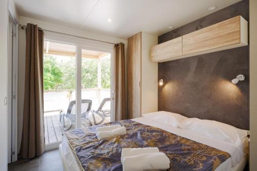 a bedroom with a large bed and a balcony at Mobile Homes - FKK Nudist Camping Solaris in Poreč