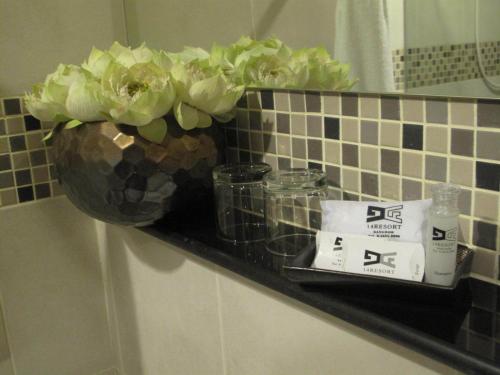 ein Regal in einem Badezimmer mit einer Vase aus Blumen in der Unterkunft 14 Resort in Bangkok