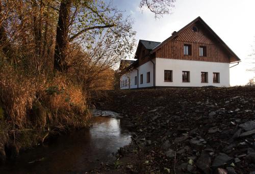 a house sitting on a hill next to a river at Penzion Terezka in Králíky
