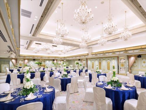 a banquet hall with blue tables and chairs and chandeliers at Hotel Plumm in Yokohama
