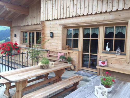 a wooden cabin with a table and benches on a balcony at Bergpension-Ebental in Brixen im Thale