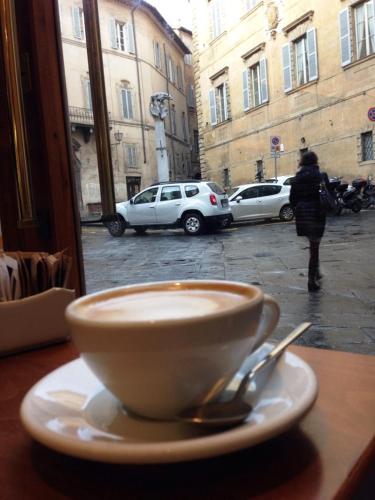 a cup of coffee sitting on a table with a spoon at B&B Quattro Cantoni in Siena