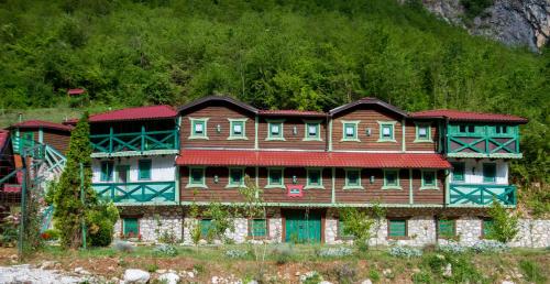 a large wooden house with blue windows on a mountain at Eco village Raj u raju in Konjic