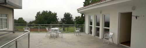 a patio with chairs and tables on a balcony at Cruce de Caminos Arzúa in Arzúa