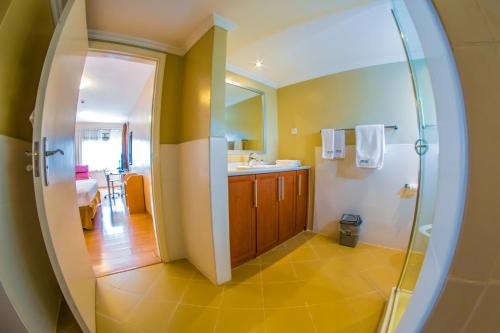 ein Bad mit einem Waschbecken und einer Dusche mit einem Spiegel in der Unterkunft Constellation Apartments in Kampala