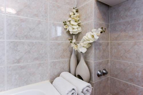 ein Bad mit einem WC und Blumen an der Wand in der Unterkunft Apartments Čolak in Zadar