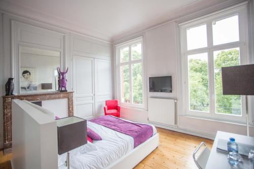 a white bedroom with a bed and a red chair at L'Esplanade Lille in Lille