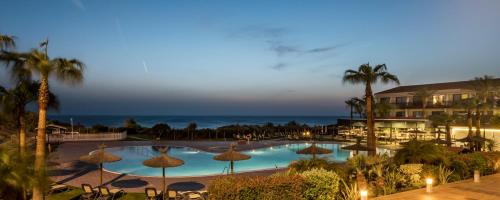 a view of a pool with umbrellas and the ocean at Ilunion Calas de Conil in Conil de la Frontera