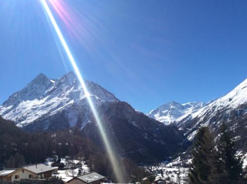 a view of a snow covered mountain with the sun shining at Hotel de la Sage in La Sage