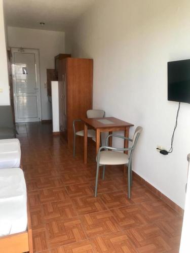 a living room with a table and chairs and a television at Kostas Studios in Faliraki
