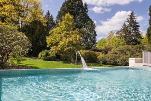 a swimming pool in a garden with a fountain at Rudding Park in Harrogate