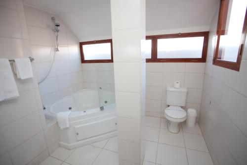 a white bathroom with a tub and a toilet and a sink at Hotel Villa Antigua in Sucre