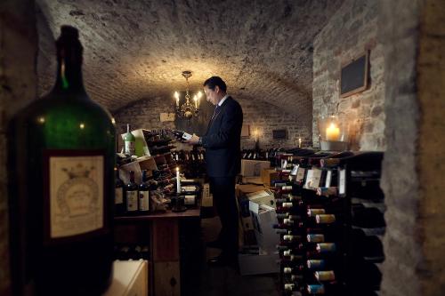 a man in a suit standing behind a bottle of wine at Buitenplaats Kasteel Elsloo in Elsloo