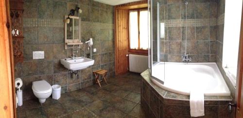 a bathroom with a tub and a toilet and a sink at Hotel de la Sage in La Sage