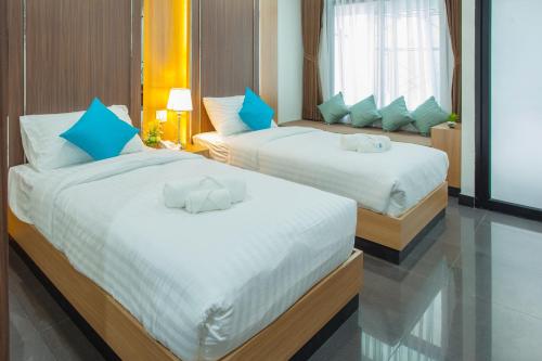 Thanburi Hotel في أودون ثاني: غرفة نوم بسريرين مع وسائد زرقاء وبيضاء