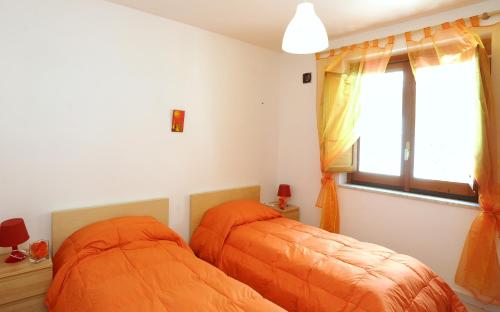 two beds in a bedroom with orange sheets at Amalfi Coast Houses in Atrani