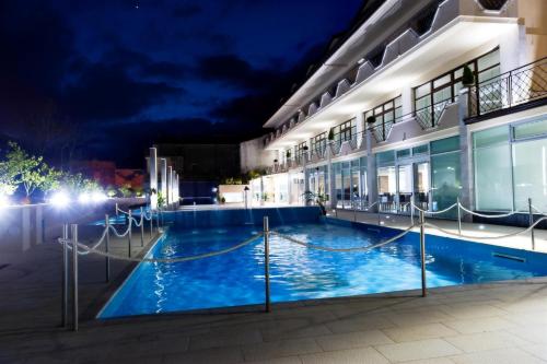a swimming pool in front of a building at night at Vea Resort Hotel in Mercato San Severino
