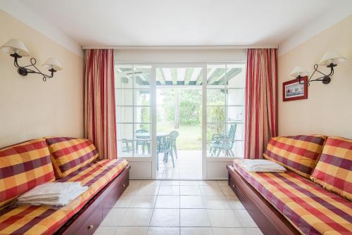 ビスカロッスにあるResidence Le Domaine de Gascogne - maeva Homeのリビングルーム(ソファ2台付)、バルコニーが備わります。