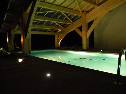 - une piscine avec un toit en bois la nuit dans l'établissement Les Etoiles du Berger, à Verrières