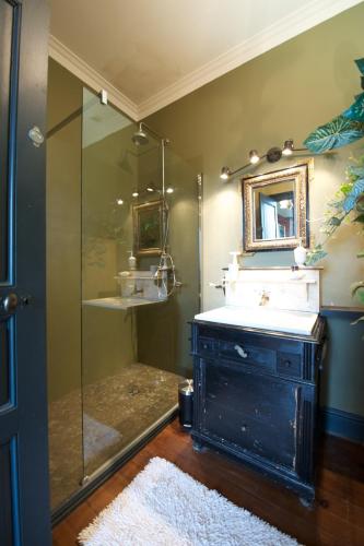 une salle de bain avec une douche avec un lavabo et un miroir dans l'établissement Château de Baylac, à Bugnein