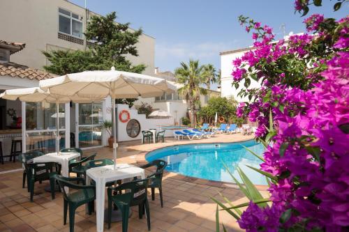 un complejo con piscina, mesas y flores púrpuras en Hotel Sultán, en Can Picafort