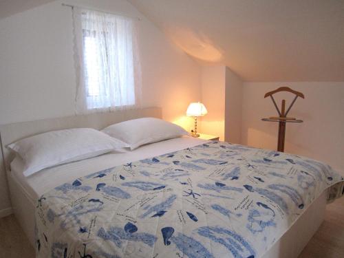 a bedroom with a bed with a blue and white comforter at Kuća za odmor Maruška in Mali Drvenik