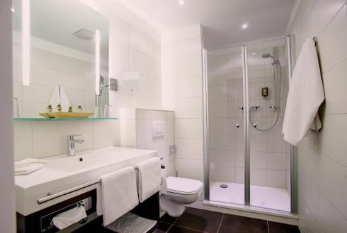 a white bathroom with a toilet and a shower at Hotel Mercedes City in Bonn