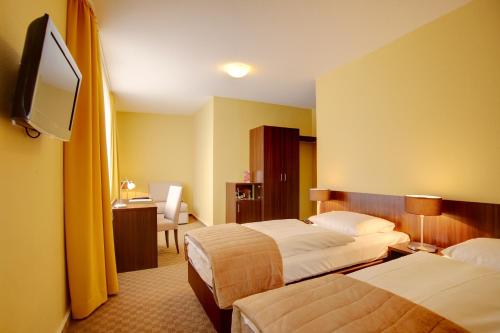 ボンにあるホテル メルセデス シティのベッド2台、薄型テレビが備わるホテルルームです。