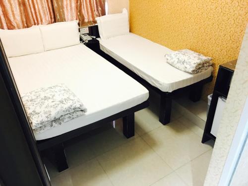 two beds in a room with white sheets at Victoria Inn in Hong Kong