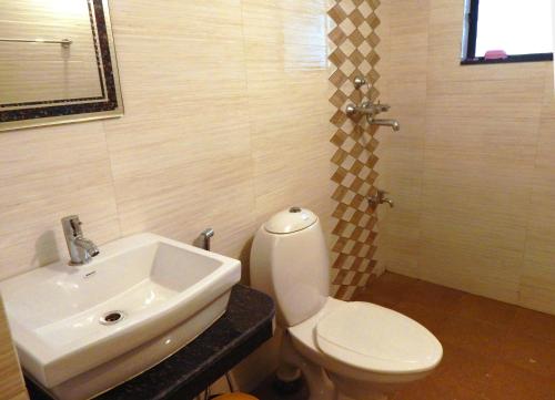 a bathroom with a white toilet and a sink at Monarch Palms- Serviced Apartments (Managed by HNH Homes) in Candolim