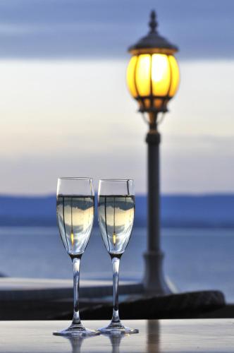 two wine glasses sitting on a table next to a lamp at Hôtel Restaurant le Panorama in Évian-les-Bains