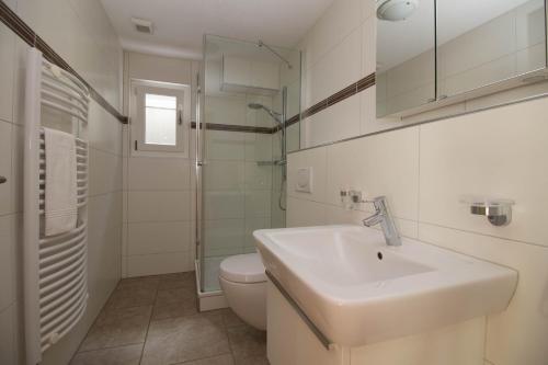 ein weißes Bad mit einem Waschbecken und einem WC in der Unterkunft Chalet Canadian Corner in Wengen