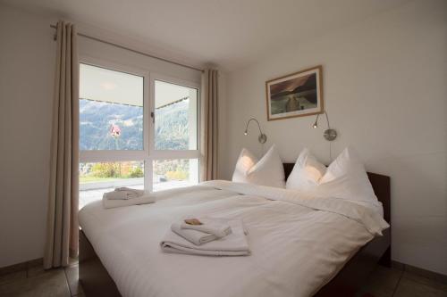 ヴェンゲンにあるChalet Canadian Cornerのベッドルーム1室(白いベッド1台、タオル付)